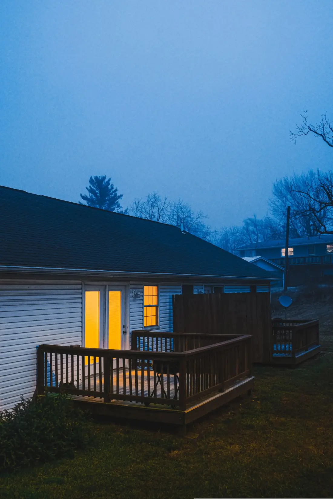 A house at dusk with warm light coming through the back door
